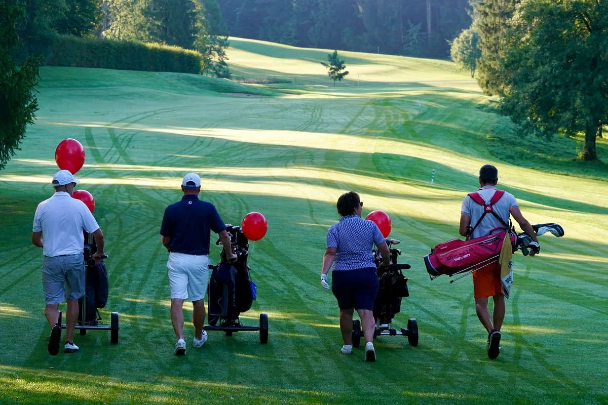 Auf zum nächsten Loch: Auch das Wetter spielte am Charity Event in Hittnau mit. Vier Golfspieler laufen über einen Golfplatz.